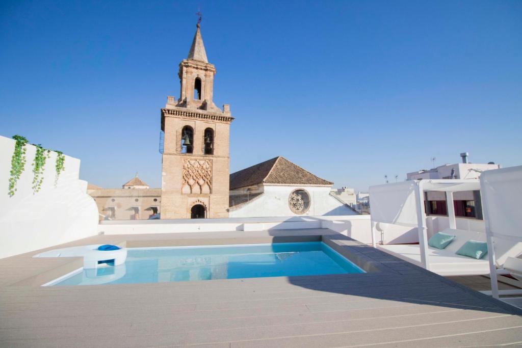 une église avec une tour d'horloge et une piscine dans l'établissement Opera Apartments - Alameda, à Séville