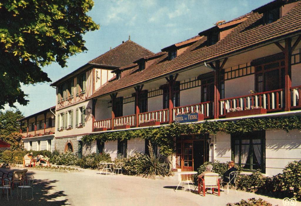 um grande edifício com mesas e cadeiras em frente em Hôtel de Tessé em Bagnoles de l'Orne