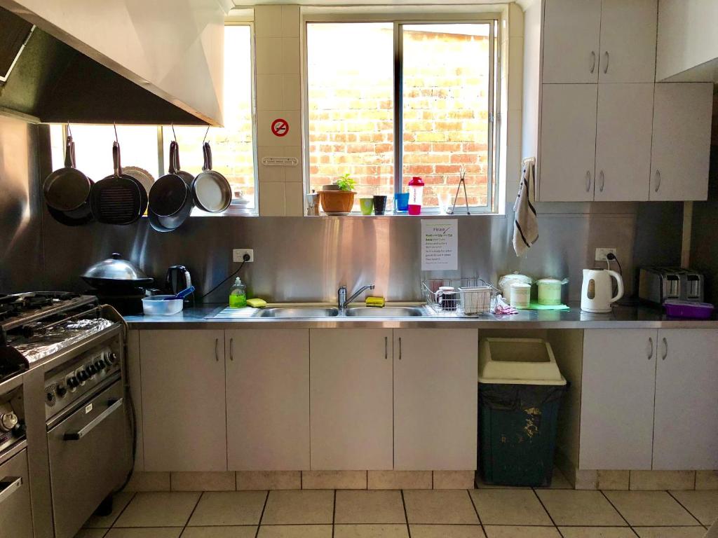 a kitchen with a stove top oven and a sink at Narrara Backpackers Hobart in Hobart