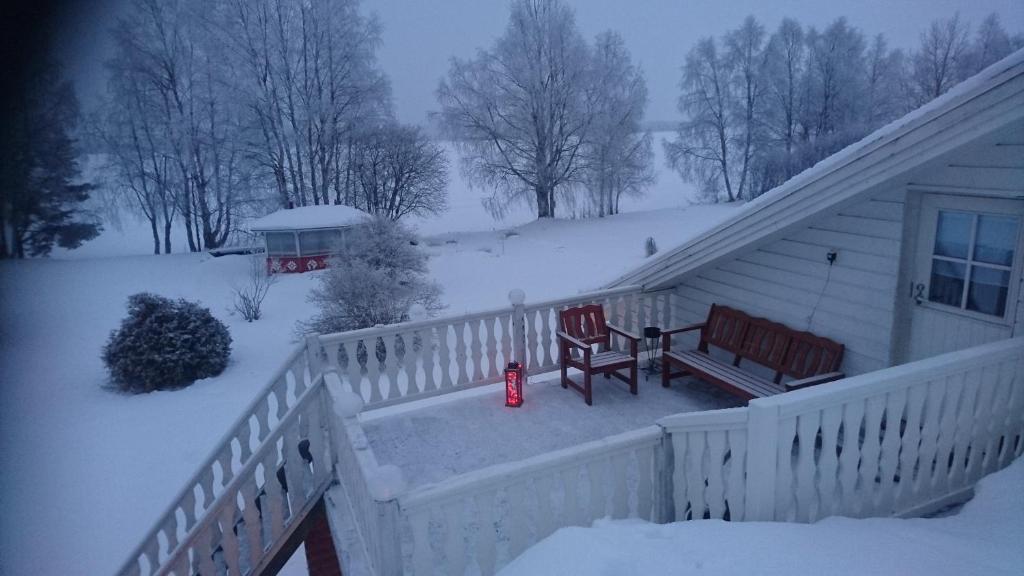 un porche couvert de neige avec deux chaises et un banc dans l'établissement Arctic River Apartment, à Rovaniemi