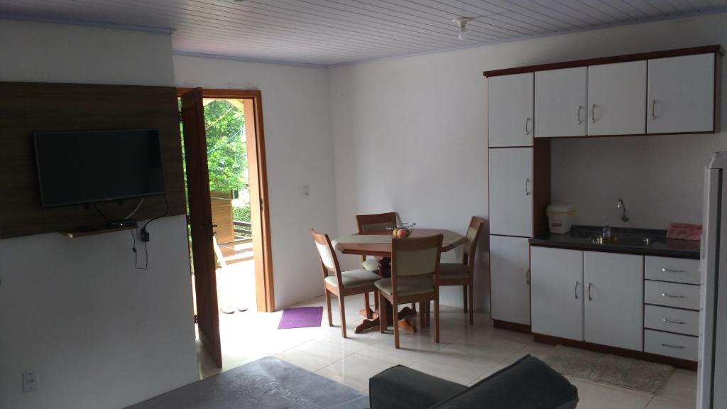 eine Küche und ein Esszimmer mit einem Tisch und einem TV in der Unterkunft Chale Verde in Gramado