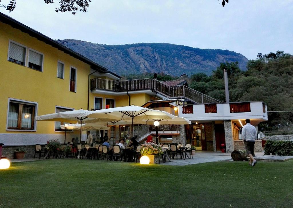 um grupo de pessoas sentadas fora de um edifício com guarda-chuvas em Hotel Castello em Montjovet