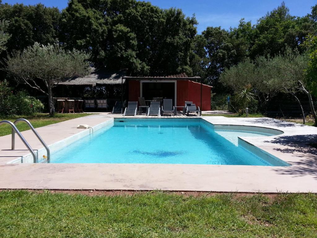 a swimming pool with chairs in a yard at Le Mas des Oliviers in Puget-Ville