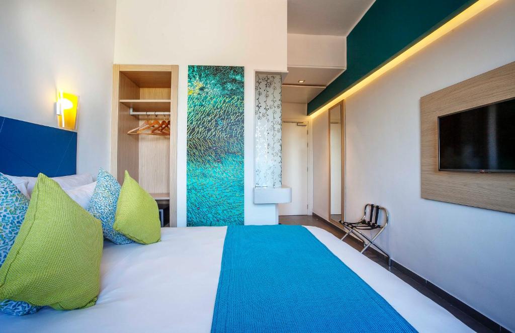 een slaapkamer met een bed met groene en blauwe kussens bij Relax Hotel Kenitra in Kenitra