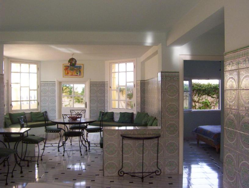 Villa Sur La Plage في الوليدية: غرفة معيشة مع طاولات وكراسي وأريكة