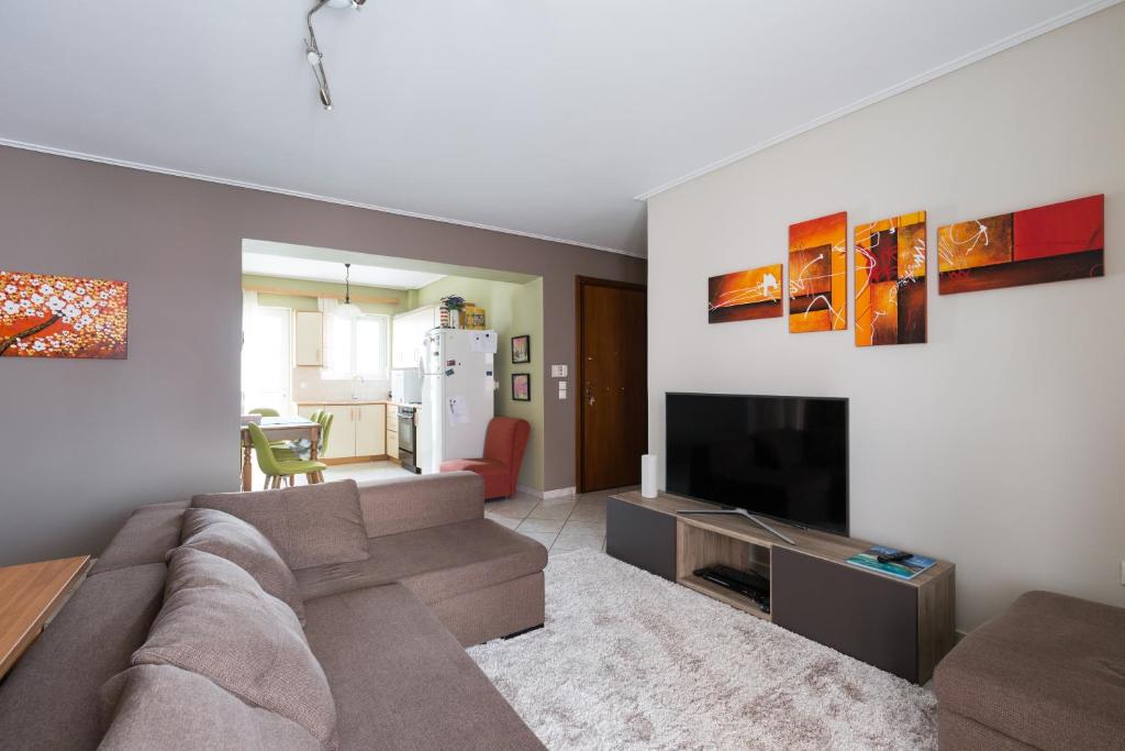 uma sala de estar com um sofá e uma televisão de ecrã plano em Holargos Metro Rooms em Atenas