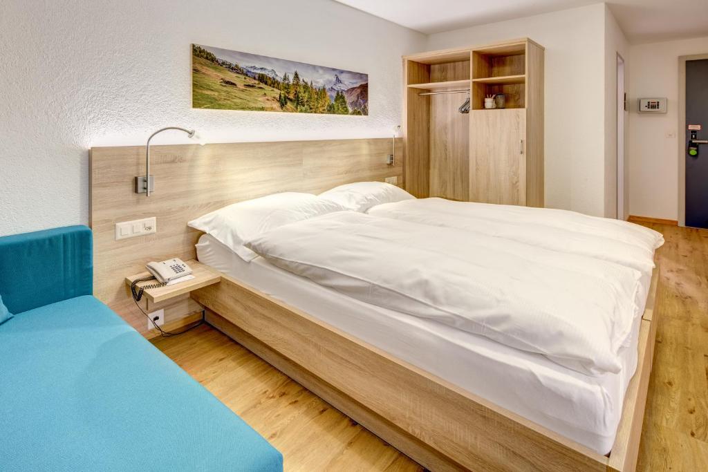 ein Schlafzimmer mit einem großen weißen Bett in einem Zimmer in der Unterkunft Matterhorn Inn in Täsch
