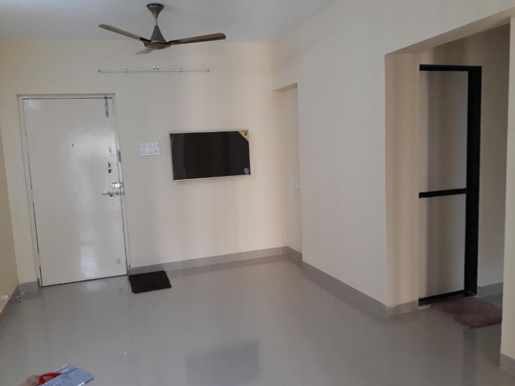 a white room with a ceiling fan and a door at Galaxy Apartment in Mumbai