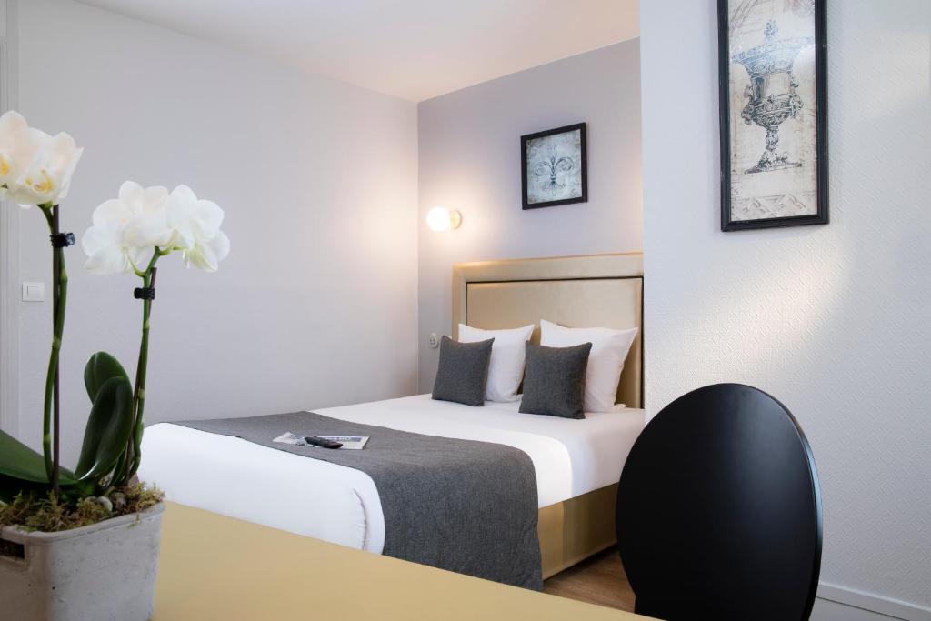 a hotel room with a bed and a desk and flowers at A l'Hôtel Des Roys in Versailles