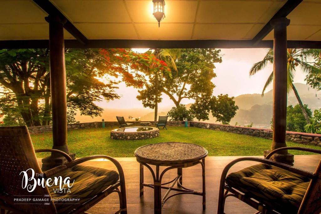 a patio with a table and chairs and a view of a yard at The Buena Vista Kandy in Kandy