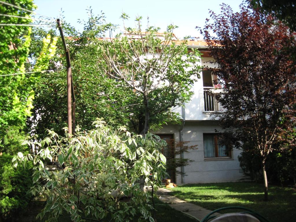 a white house with trees and bushes in front of it at Hostel Oasis in Belgrade