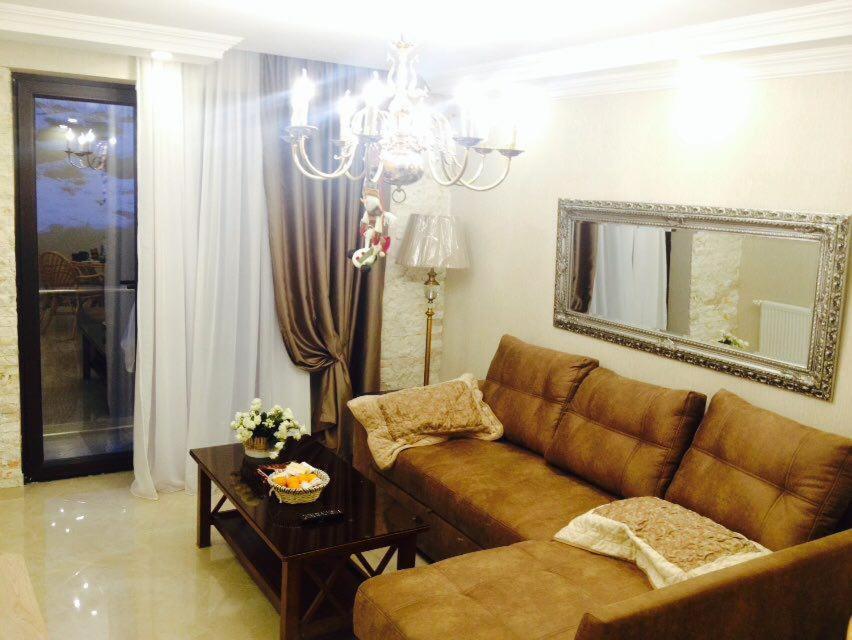 a living room with a brown couch and a mirror at Orbi Palace Bakuriani Apartment in Bakuriani