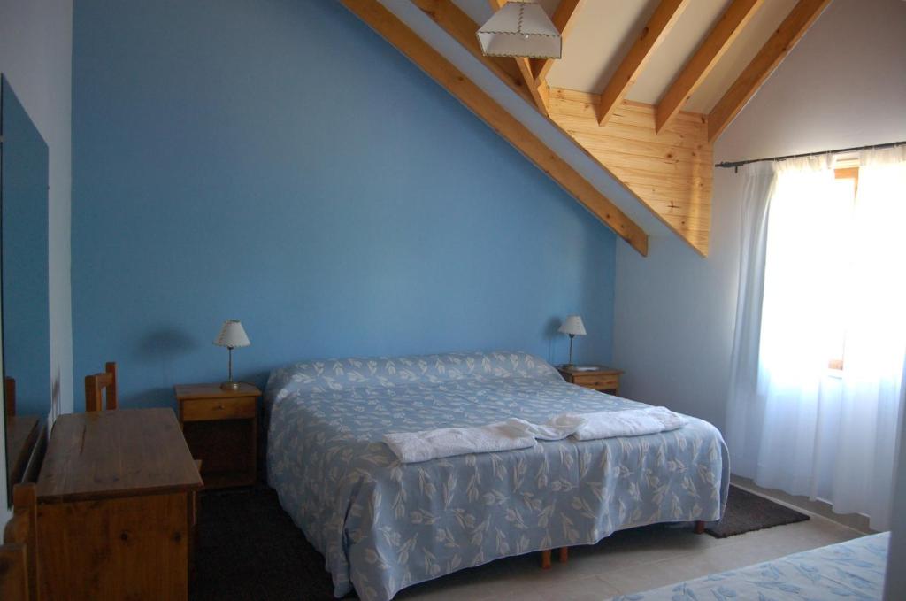 1 dormitorio con cama y pared azul en La Estancia en Trevelín