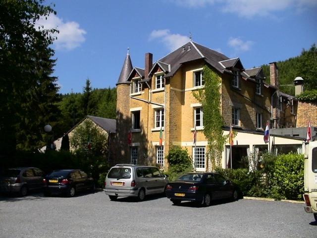 ein großes Gebäude mit Autos auf einem Parkplatz in der Unterkunft Hotel Ermitage du Moulin Labotte in Haybes