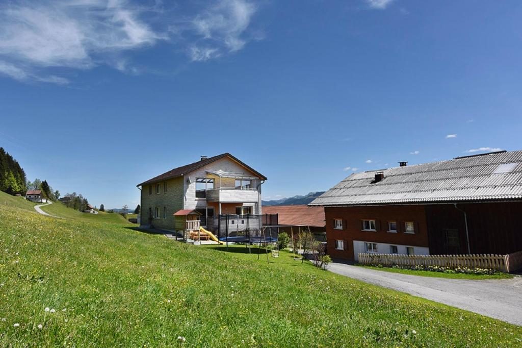 ein Haus auf einem Hügel neben einer Scheune in der Unterkunft Ferienhof Feurle in Sulzberg