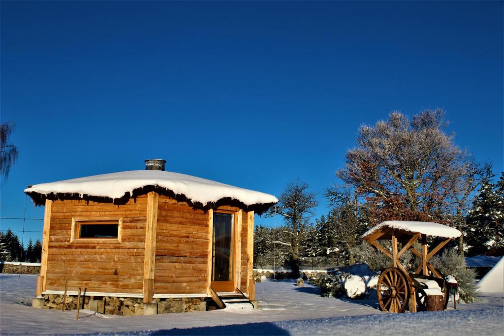 une cabane en bois dans la neige avec un wagon dans l'établissement Eco Yourte, à Sembadel