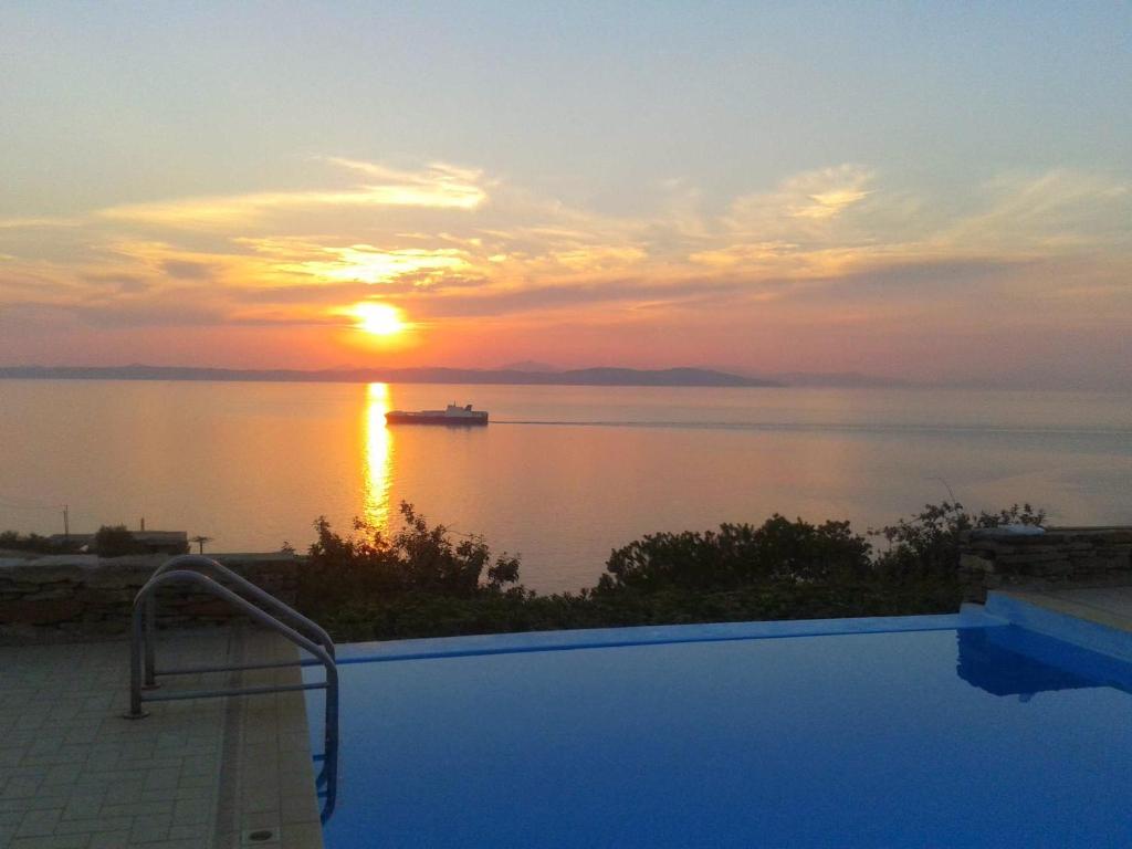 a swimming pool with a sunset over the water at Villa au paradis bleu in Melissaki