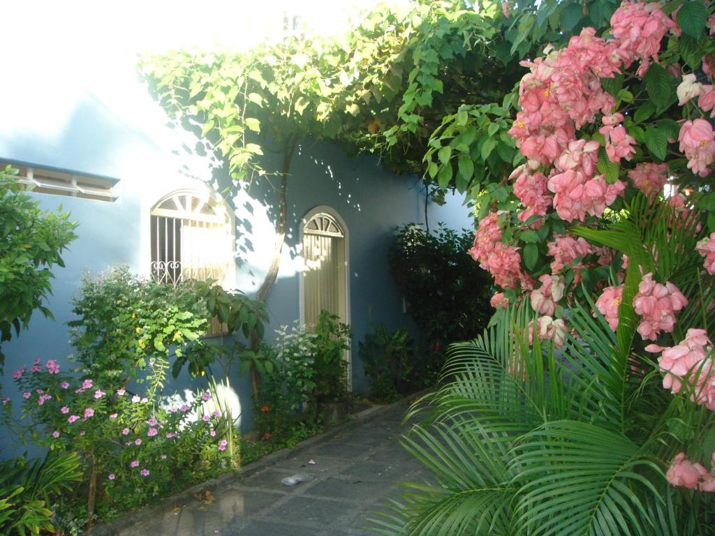 una casa azul con flores rosas y una pasarela en Vivenda Porto, conforto e estacionamento free no centro da cidade, en Porto Seguro