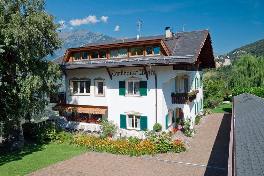 Casa blanca grande con ventanas con persianas verdes en Landhaus Weger, en Merano