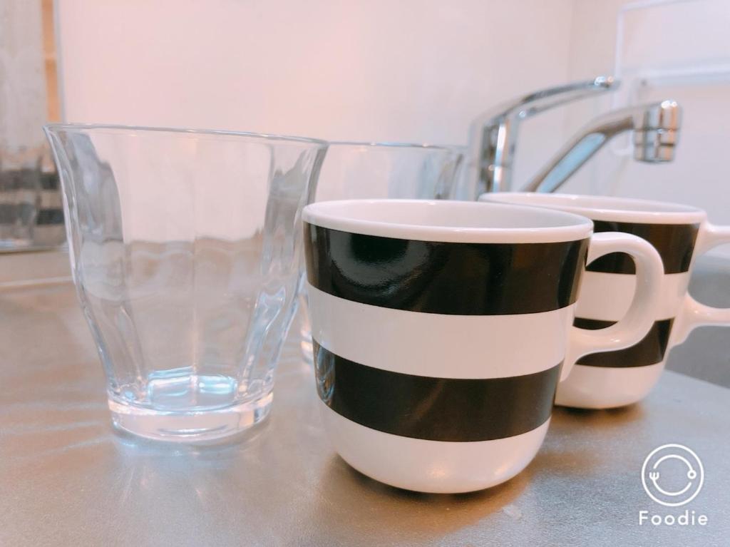 two coffee cups and a glass on a counter at Awaza House in Osaka