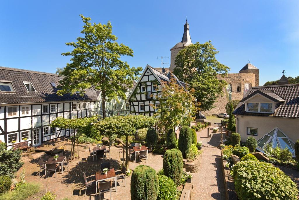 une cour d'un bâtiment avec des arbres et des buissons dans l'établissement Malerwinkel Hotel, à Bergisch Gladbach