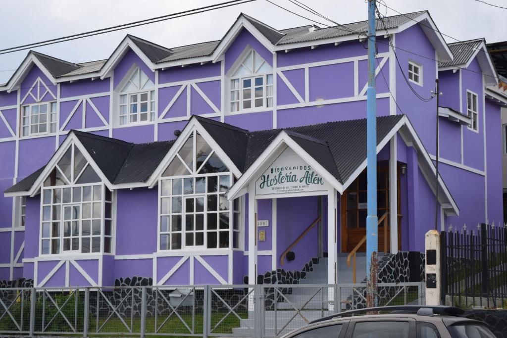un edificio púrpura con un coche aparcado delante de él en Hostería Ailen en Ushuaia