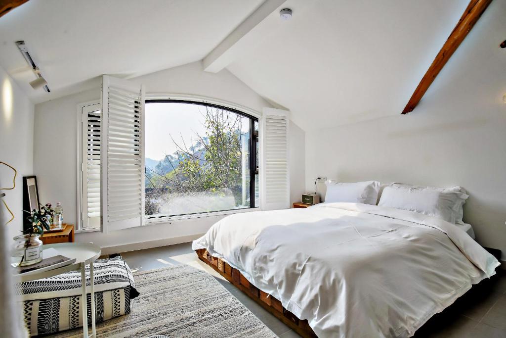 a white bedroom with a bed and a large window at Hangzhou Sansu Hotel in Hangzhou