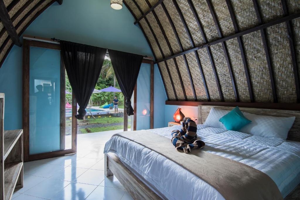 a bedroom with a bed with a teddy bear on it at Apit Lawang Villas & Resto in Nusa Penida
