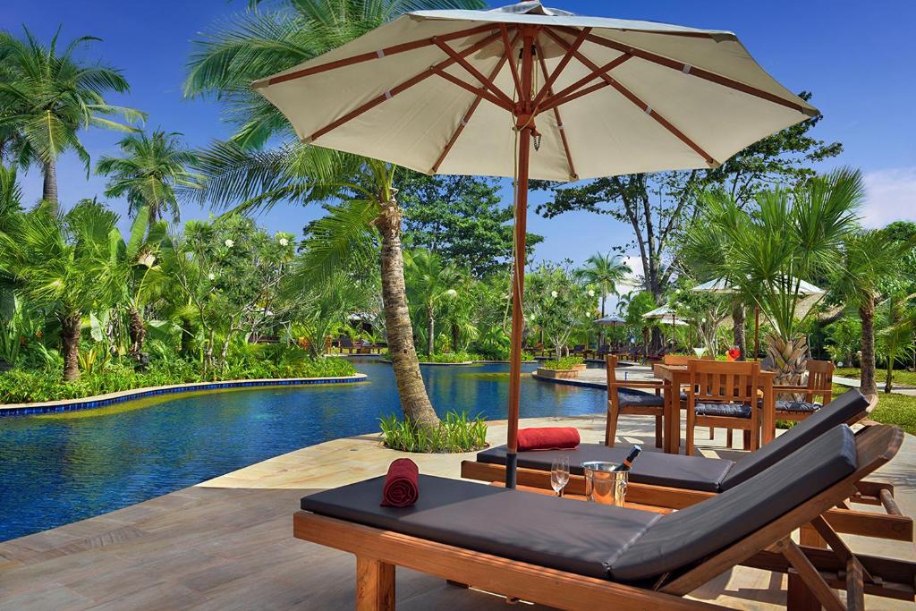 eine Terrasse mit einem Sonnenschirm neben einem Pool in der Unterkunft Mali Resort Sunrise Beach in Ko Lipe