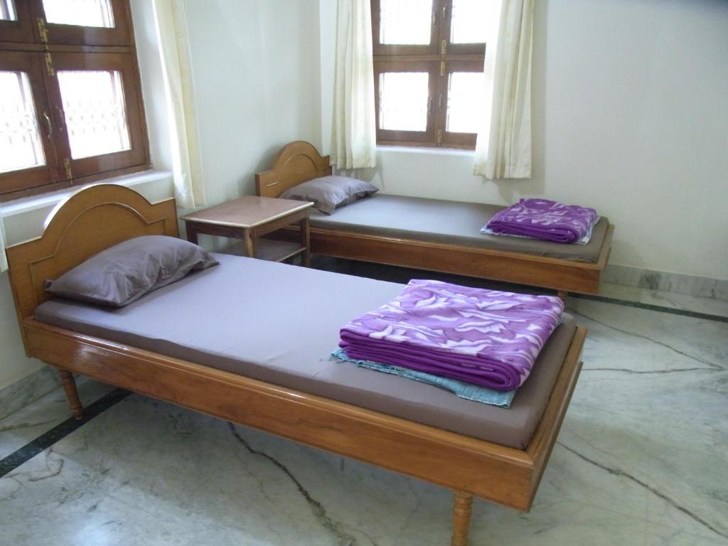 two beds sitting in a room with windows at Momotaro House in Bodh Gaya