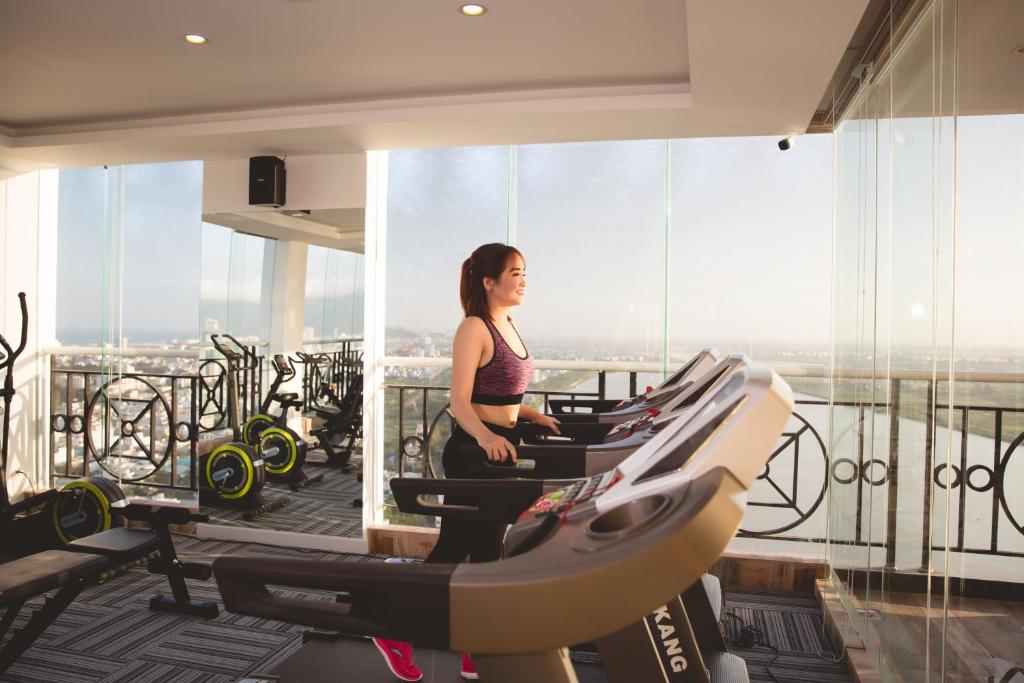 A bright fitness room with treadmills, bikes and expansive city-facing windows.