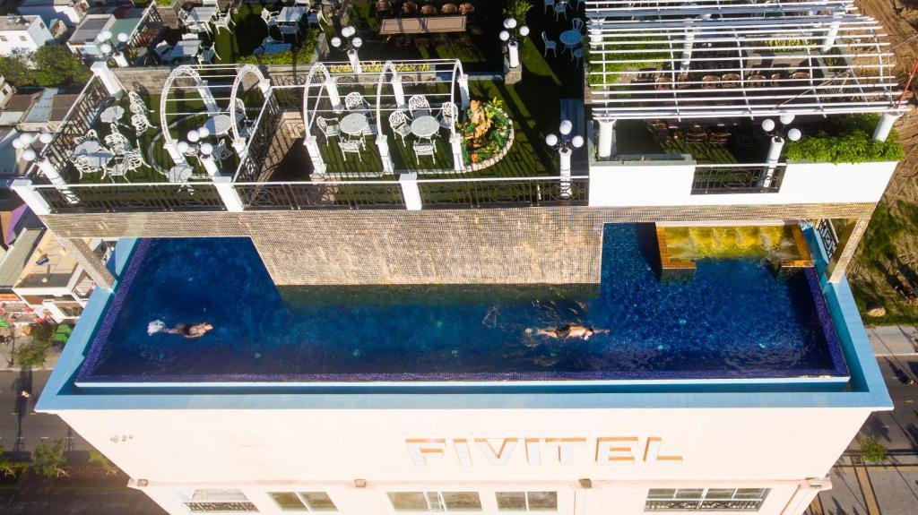 An elevated rooftop pool viewed from above, with rooftop seating and landscaping around it.