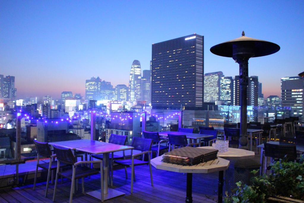 a rooftop patio with tables and chairs and a city skyline at Shinjuku Granbell Hotel in Tokyo
