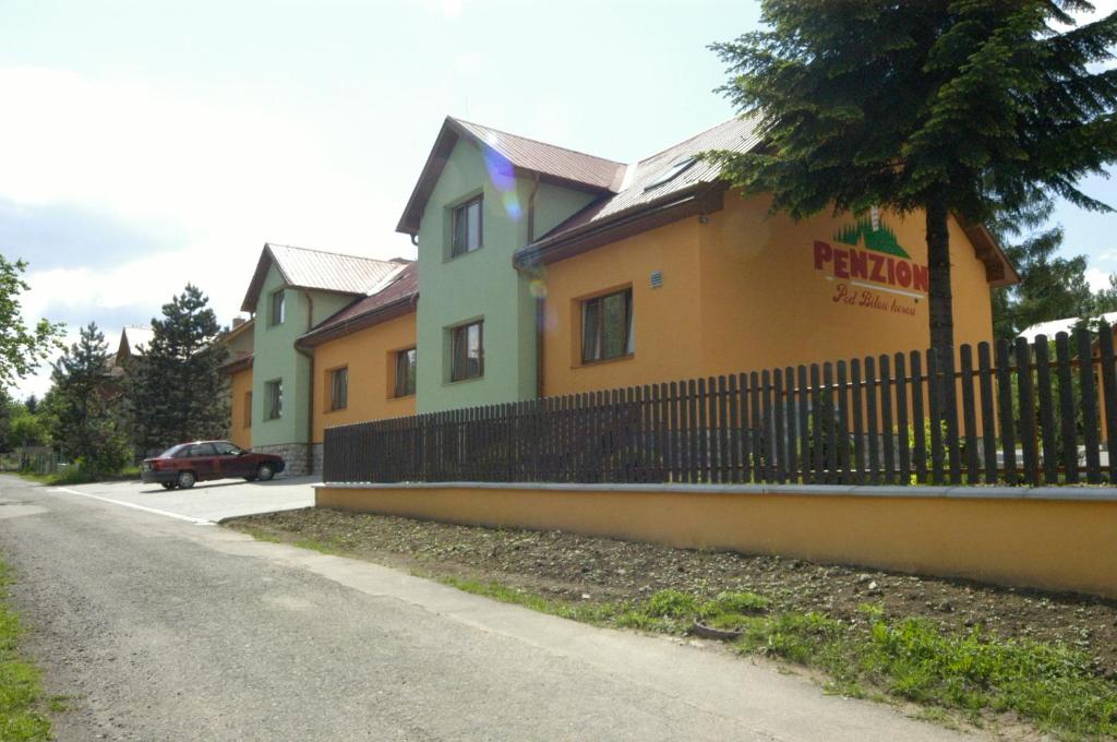 a house with a fence next to a street at Penzion pod Bílou Horou in Kopřivnice