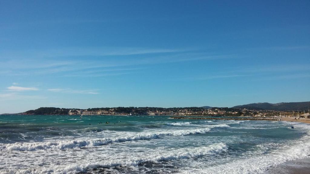 a beach with people in the water and waves at Le tauroeis in Sanary-sur-Mer