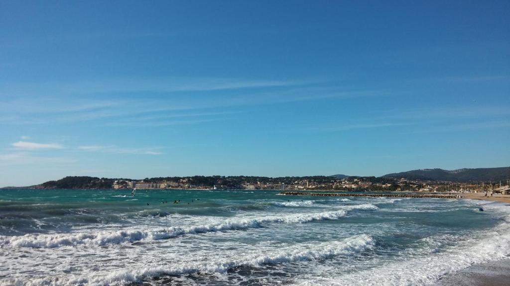 a beach with people in the water and waves at Hyper Centre Sanary 3 chambres parking balcon clim wifi in Sanary-sur-Mer