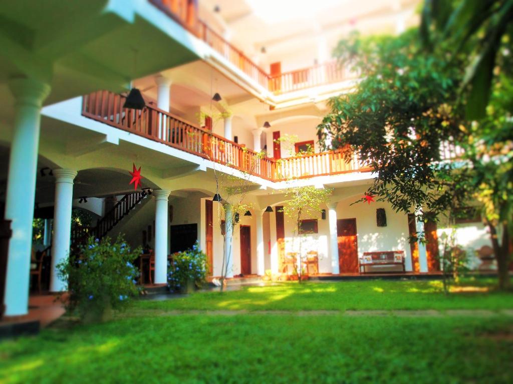 un gran edificio blanco con balcón y patio en Unawatuna Nor Lanka Hotel en Unawatuna