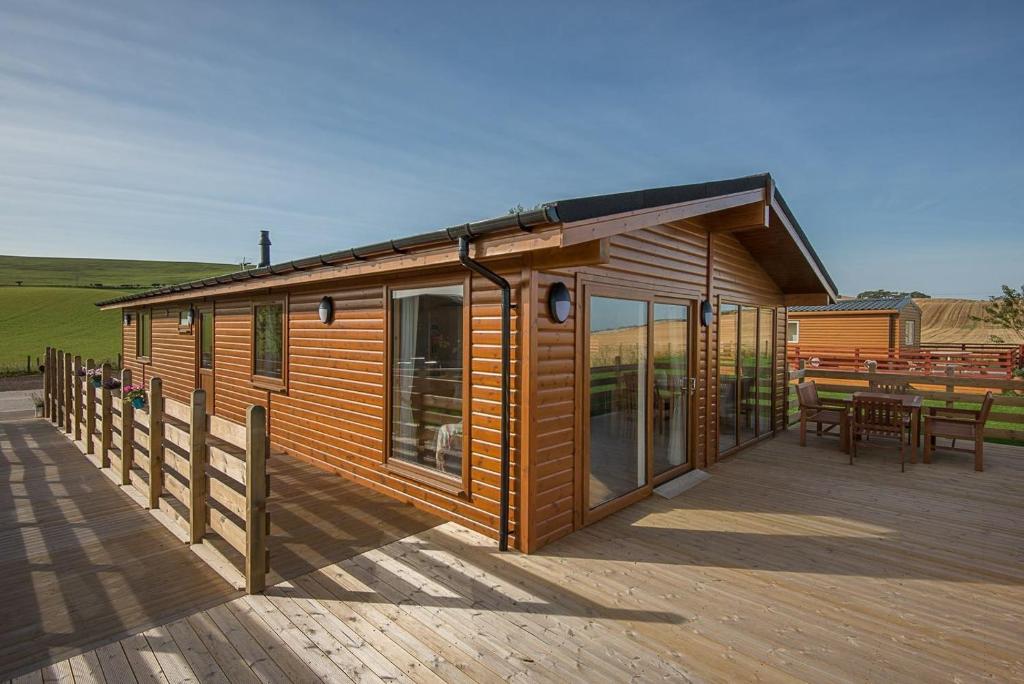 Cabaña de madera con terraza y mesa en The Chalet, Holidays for All en Dunbar