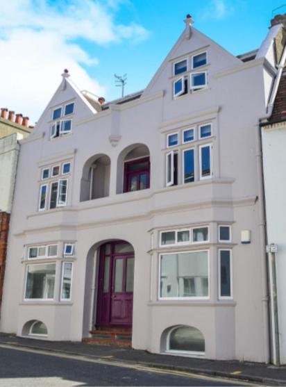 a white building with red doors on a street at Camelford House in Brighton & Hove