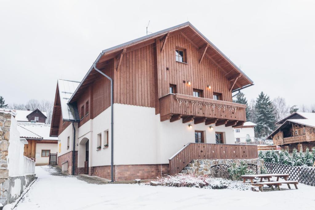 un bâtiment en bois avec un balcon dans la neige dans l'établissement Penzion U Kaplicky, à Železná Ruda