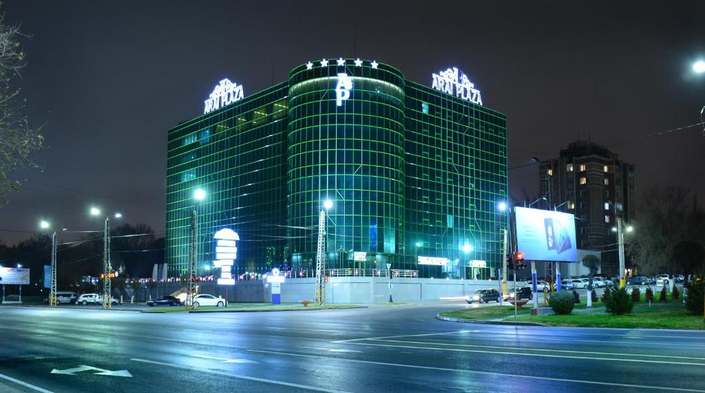 duży budynek z oświetleniem na górze w nocy w obiekcie Hotel Arai Plaza w mieście Taraz