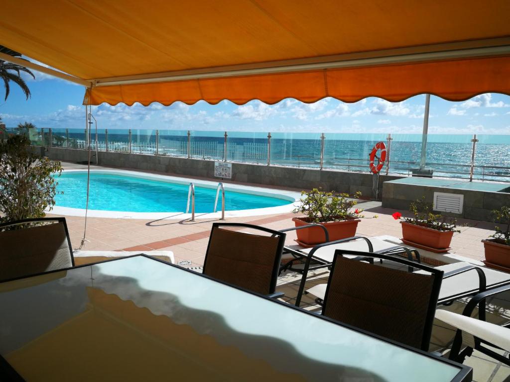 a swimming pool with a table and chairs and the ocean at Samoa Lovely Seaview in Playa del Ingles