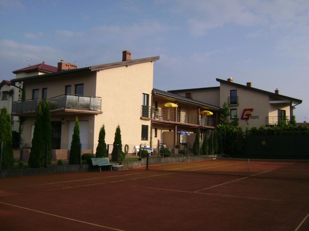 een gebouw met een tennisbaan ervoor bij Galeria Tennis in Grzybowo