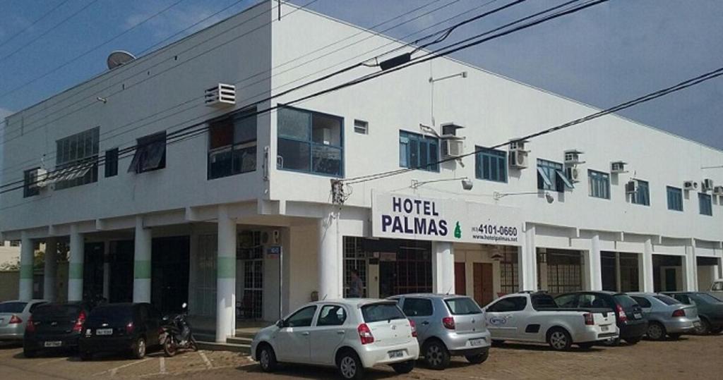 een wit gebouw met auto's geparkeerd op een parkeerplaats bij Hotel Palmas Tocantins in Palmas