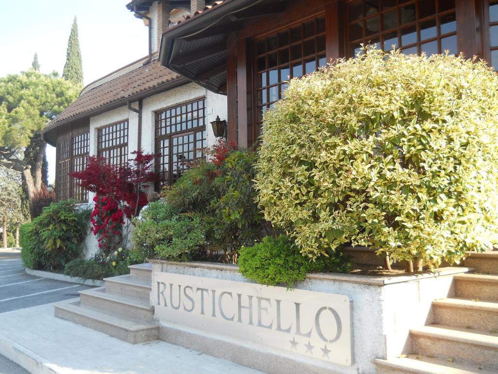 a sign in front of a building with bushes at Hotel Il Rustichello in Lonato del Garda