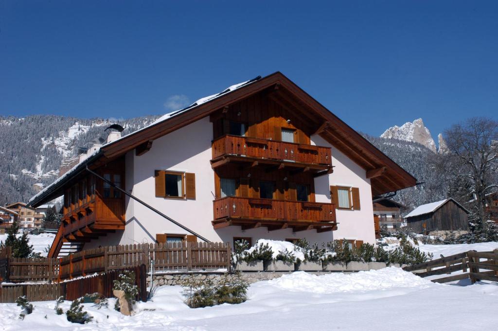 a house with a balcony in the snow at Appartamenti Majon Ladina in Vigo di Fassa