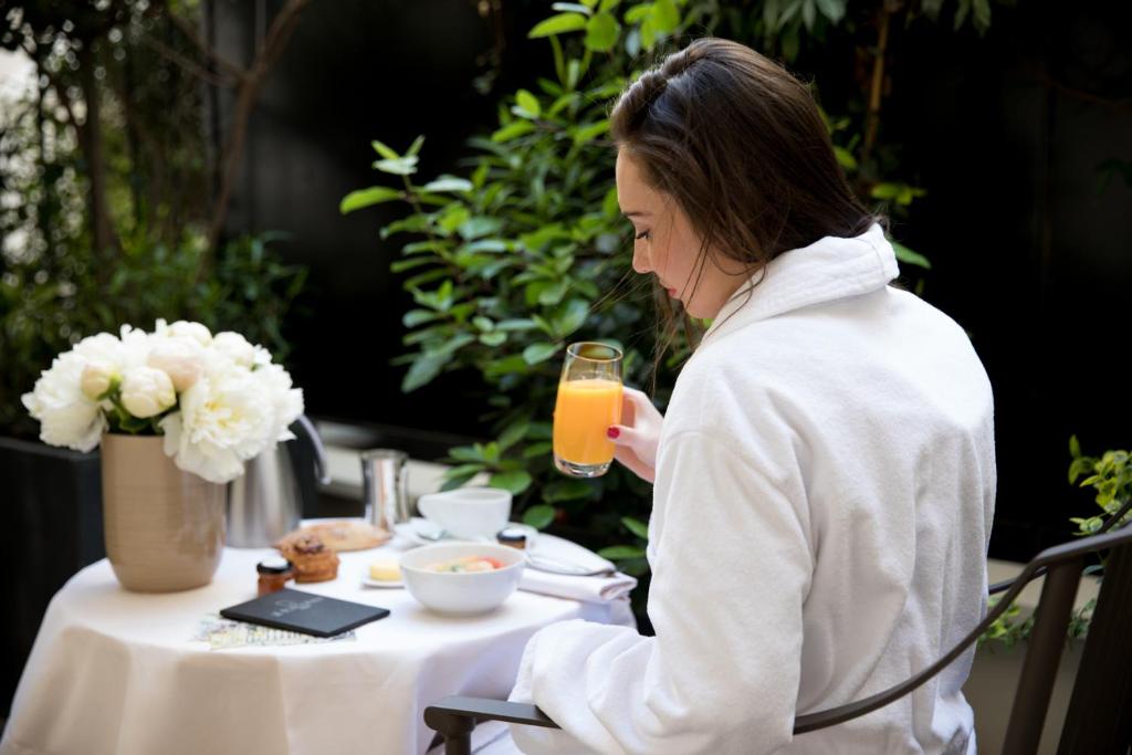 a woman sitting at a table with a glass of orange juice at Le Burgundy Paris in Paris