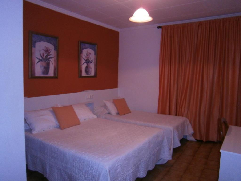 two beds in a hotel room with orange walls at Hostal Don Pepe in Figueres