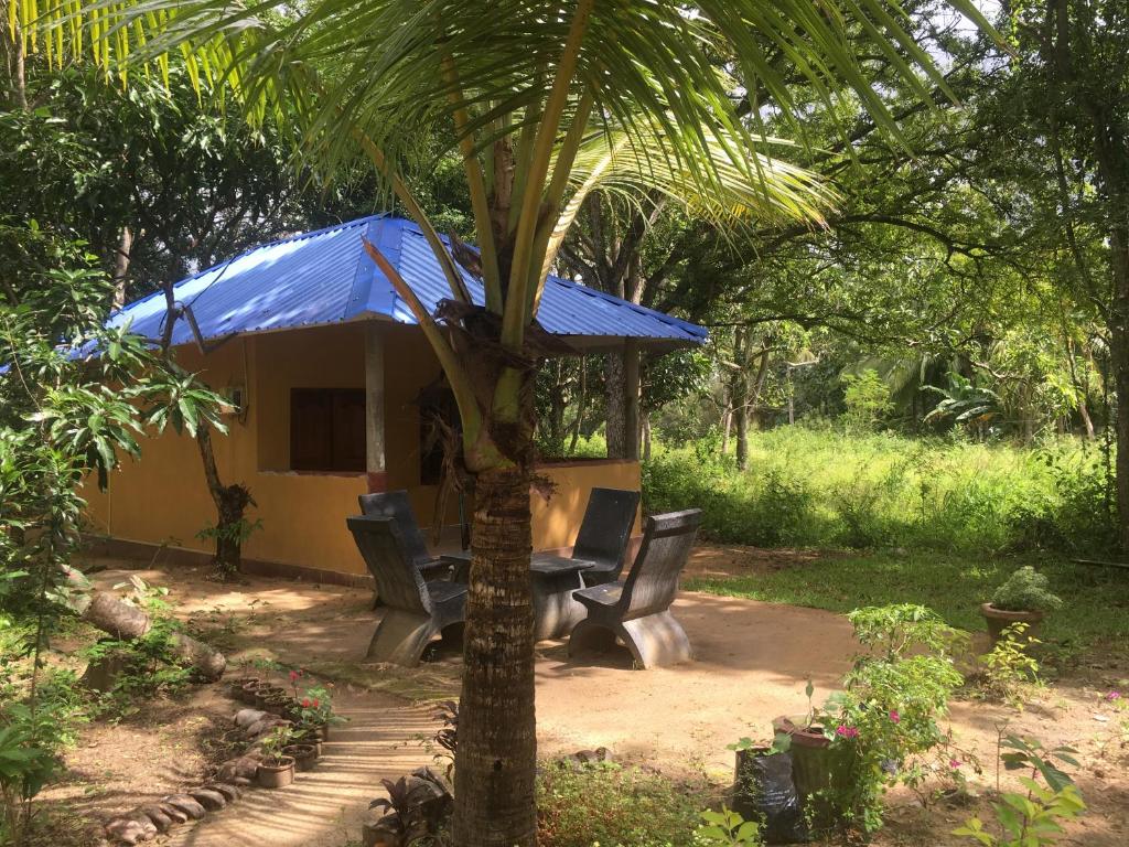 een tafel en stoelen voor een huis met een palmboom bij Yapahuwa Relax Stay in Yapahuwa