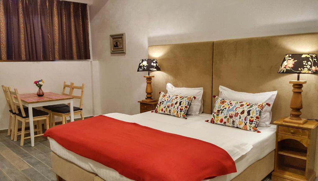 um quarto com uma cama com um cobertor vermelho e uma mesa em Windmill Studios by Rembrandt Hotel em Bucareste